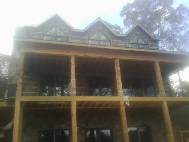 Dormers and porch framing on a large log home under construction — Roof Coating work by our crew in Hillside